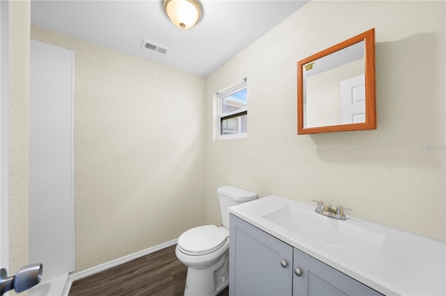 bathroom featuring toilet, baseboards, visible vents, vanity, and wood finished floors