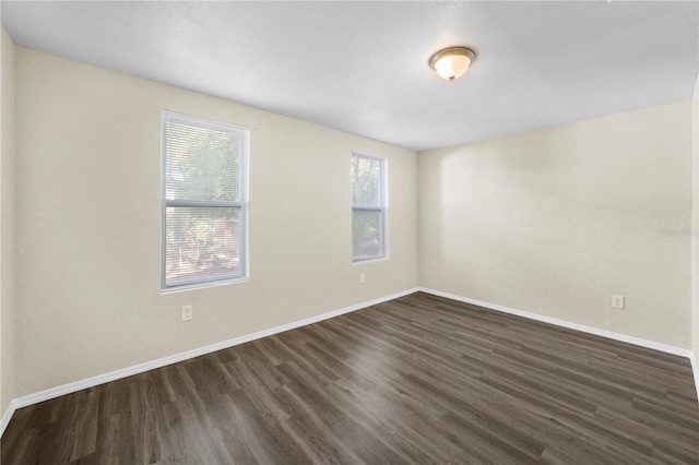 spare room featuring baseboards and dark wood-style floors