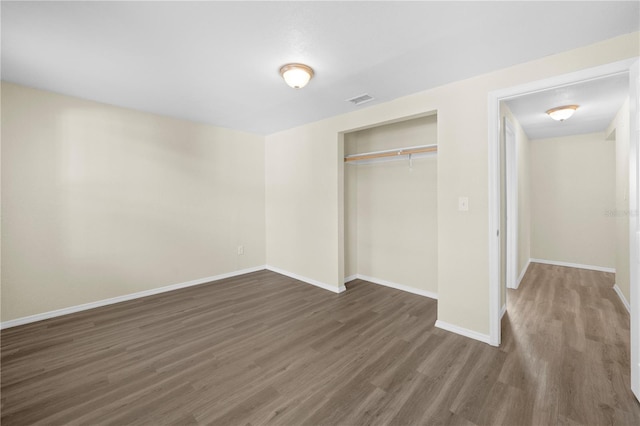 unfurnished bedroom with baseboards, a closet, visible vents, and wood finished floors