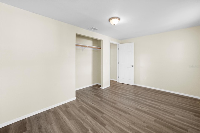 unfurnished bedroom featuring a closet, visible vents, baseboards, and dark wood-style floors