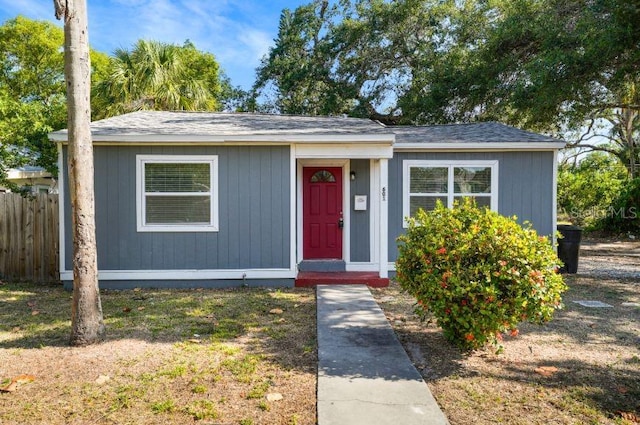 bungalow with a shingled roof and fence