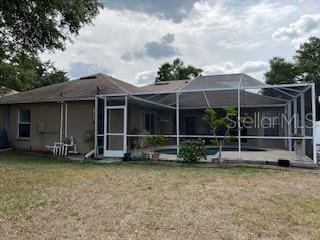 back of house featuring a yard, a lanai, and an outdoor pool