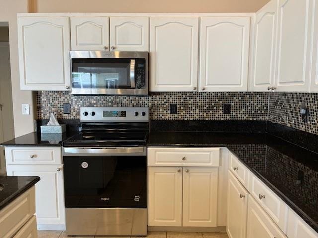 kitchen with dark stone counters, appliances with stainless steel finishes, backsplash, and white cabinets
