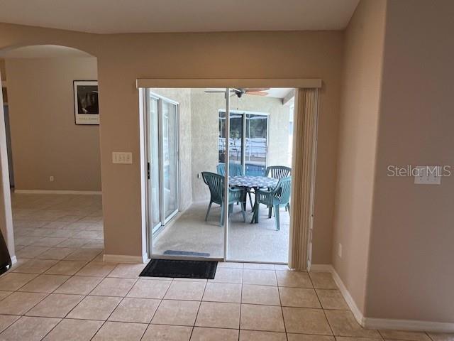 dining area featuring light tile patterned floors, baseboards, ceiling fan, and arched walkways