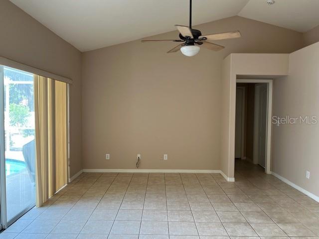 unfurnished room with light tile patterned floors, baseboards, a ceiling fan, and lofted ceiling