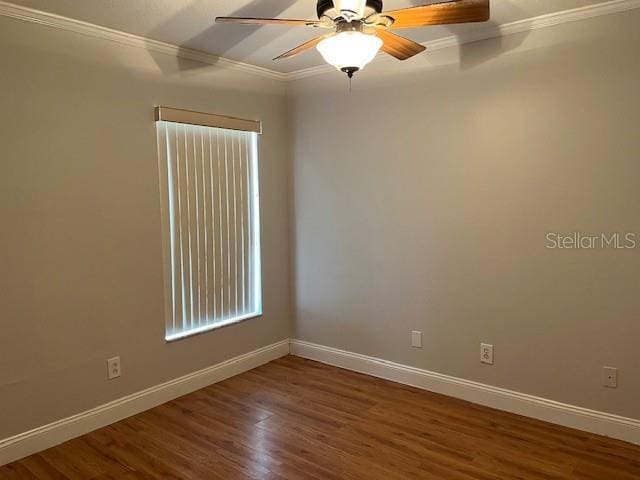 spare room with baseboards, ornamental molding, and wood finished floors