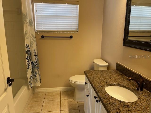 full bath with vanity, toilet, baseboards, tile patterned floors, and shower / bath combo