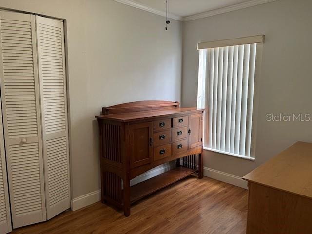 bedroom featuring a closet, ornamental molding, baseboards, and wood finished floors