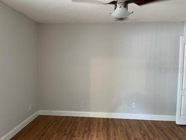 unfurnished room featuring baseboards and dark wood-style flooring