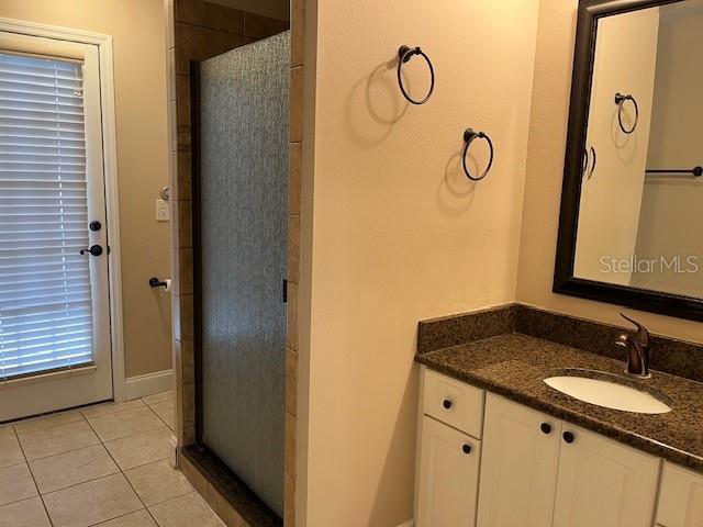 bathroom featuring tile patterned floors, a tile shower, and vanity