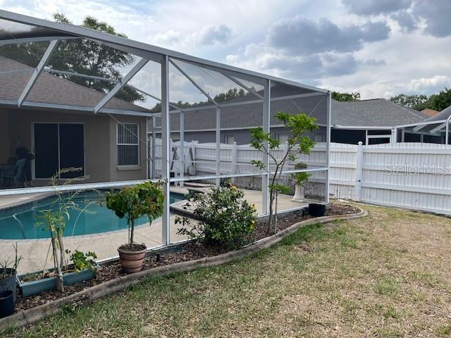 view of pool with glass enclosure, a lawn, fence private yard, and a patio area