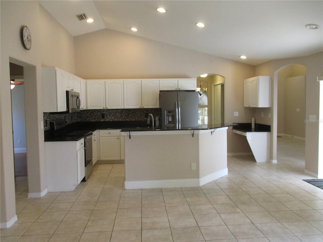 2213 Towering Oaks Cir, Seffner, FL 33584 - kitchen featuring stainless steel appliances, light tile patterned flooring, arched walkways, white cabinetry, and dark countertops