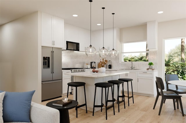 kitchen with a sink, appliances with stainless steel finishes, light wood finished floors, and white cabinetry