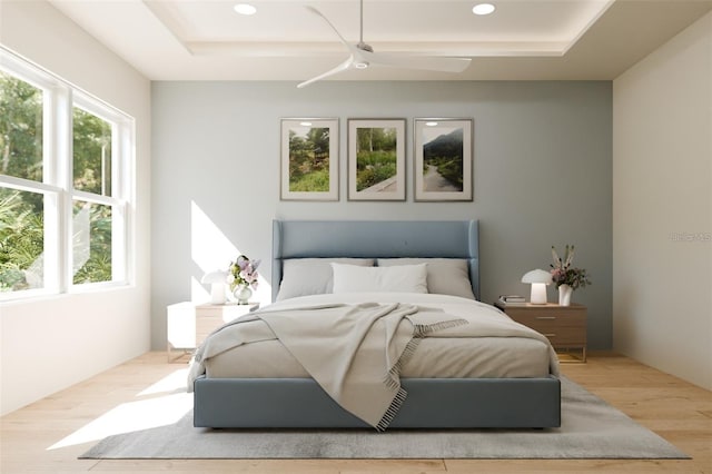 bedroom with a ceiling fan, a tray ceiling, recessed lighting, and wood finished floors