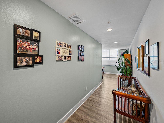 corridor featuring wood finished floors, recessed lighting, and baseboards
