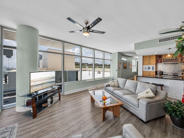 living area with a ceiling fan, wood finished floors, and baseboards