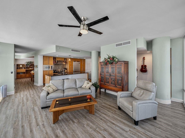 living room with light wood-style flooring, baseboards, and a ceiling fan
