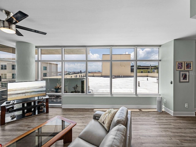 living area with baseboards, wood finished floors, and ceiling fan