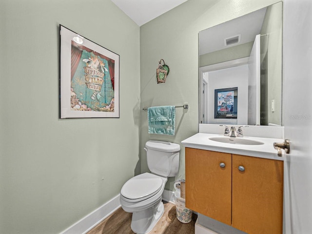 bathroom featuring wood finished floors, baseboards, toilet, and vanity