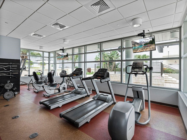 exercise room with healthy amount of natural light, baseboards, and a drop ceiling
