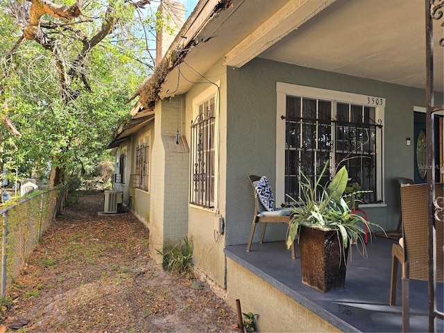 view of property exterior with brick siding, central AC, fence, and stucco siding