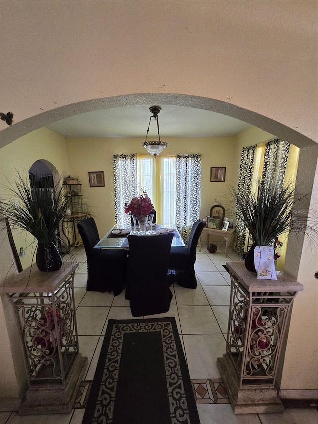 dining room with arched walkways and light tile patterned floors