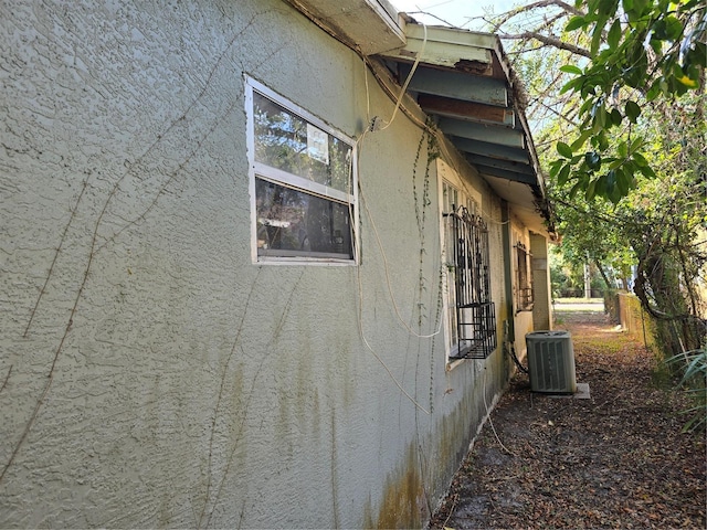 view of side of property featuring central AC unit and stucco siding