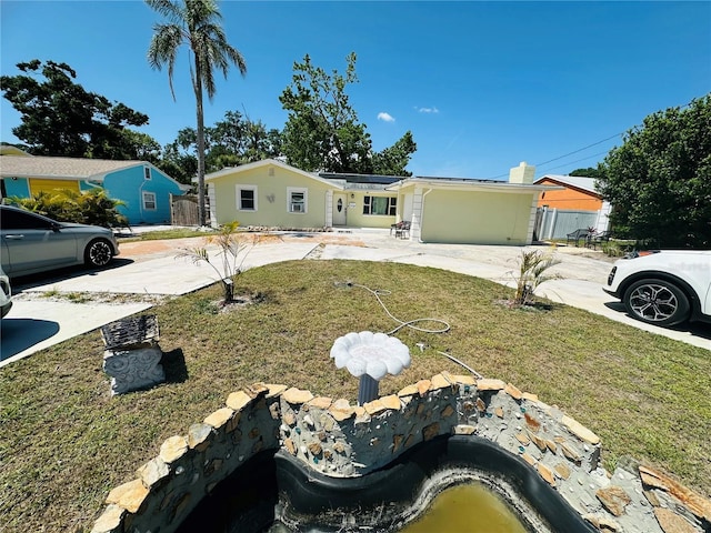 1101 Alcazar Way S, Saint Petersburg, FL 33705 - view of front of home with roof mounted solar panels, fence, driveway, and a front yard