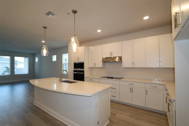 kitchen with visible vents, wood finished floors, under cabinet range hood, a sink, and black appliances