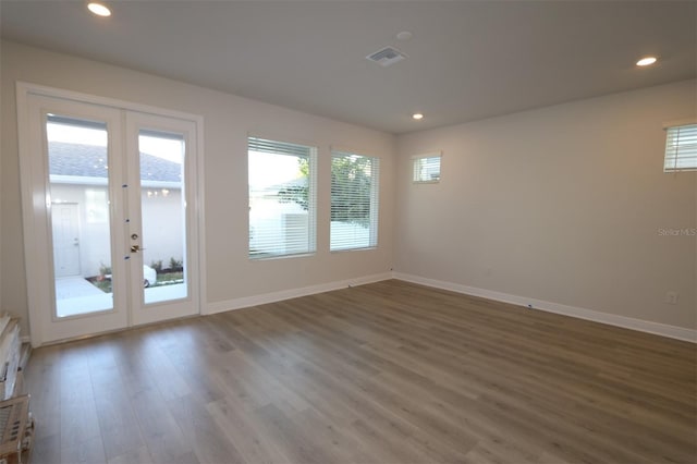 spare room featuring baseboards, french doors, wood finished floors, and a wealth of natural light