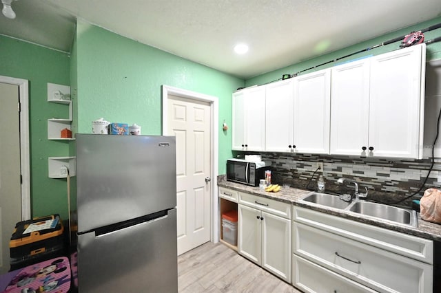 11314 Silverleaf Ct, Riverview, FL 33579 - kitchen featuring freestanding refrigerator, black microwave, light wood-style floors, backsplash, and white cabinets