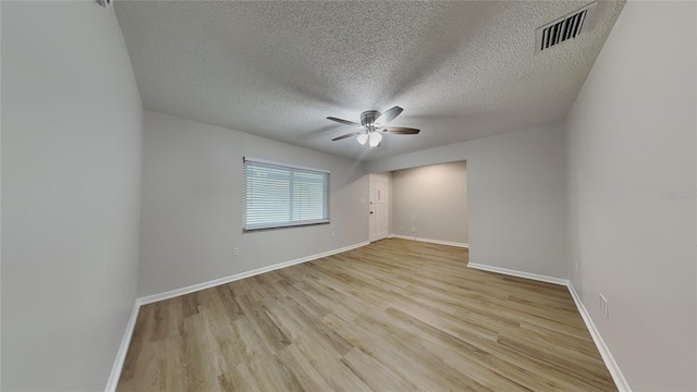 empty room with a textured ceiling, baseboards, a ceiling fan, and visible vents