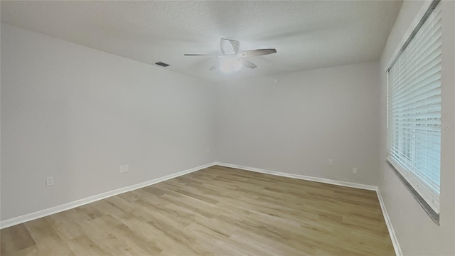 unfurnished room with a ceiling fan, baseboards, light wood-style flooring, and visible vents