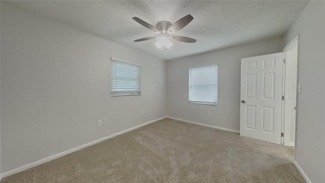 carpeted empty room featuring baseboards, ceiling fan, and a textured ceiling
