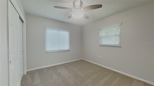 unfurnished bedroom featuring a closet, a textured ceiling, multiple windows, and carpet