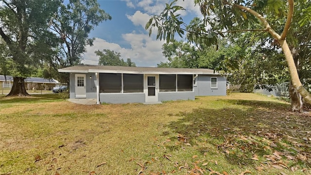 back of property featuring a lawn and a sunroom