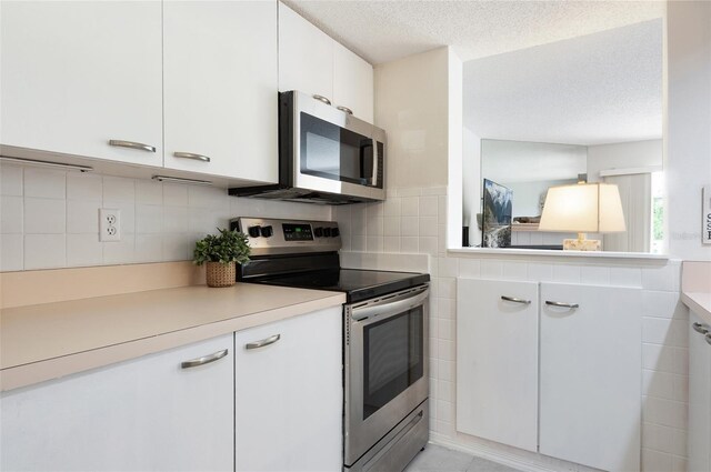 623 Garland Cir, Indian Rocks Beach, FL 33785 - kitchen with appliances with stainless steel finishes, a textured ceiling, white cabinets, light countertops, and tasteful backsplash