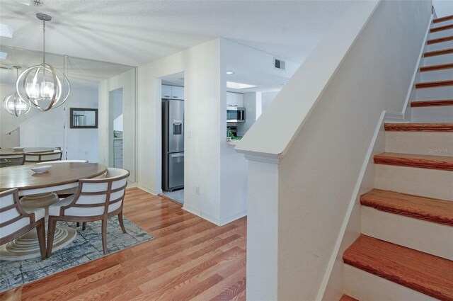 623 Garland Cir, Indian Rocks Beach, FL 33785 - dining area with stairway, light wood-type flooring, and a chandelier