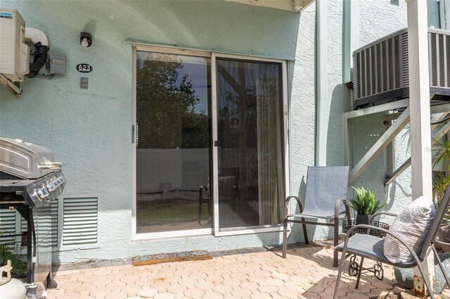623 Garland Cir, Indian Rocks Beach, FL 33785 - property entrance with stucco siding, a patio area, and central AC unit