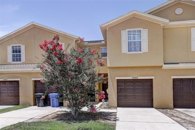 townhome / multi-family property with a garage, stucco siding, and concrete driveway