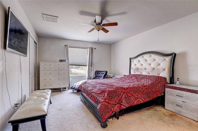 bedroom featuring visible vents, a textured ceiling, carpet floors, and ceiling fan