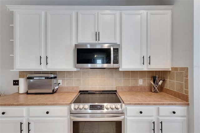 10636 Dawns Light Dr, Riverview, FL 33578 - kitchen with stainless steel appliances, light countertops, white cabinets, backsplash, and open shelves