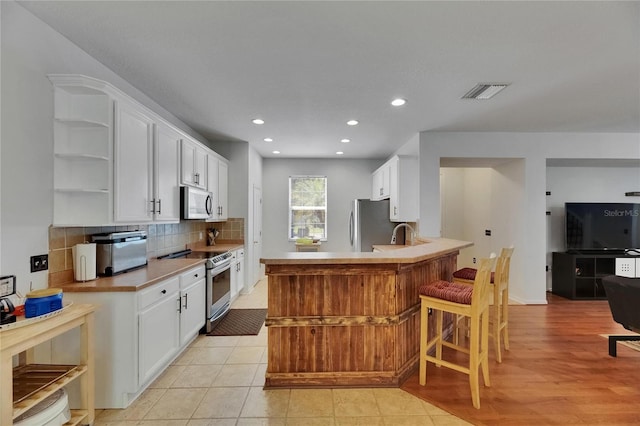 10636 Dawns Light Dr, Riverview, FL 33578 - kitchen featuring appliances with stainless steel finishes, open shelves, white cabinetry, tasteful backsplash, and recessed lighting