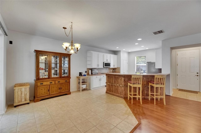 10636 Dawns Light Dr, Riverview, FL 33578 - kitchen featuring appliances with stainless steel finishes, a chandelier, white cabinetry, a peninsula, and a breakfast bar area