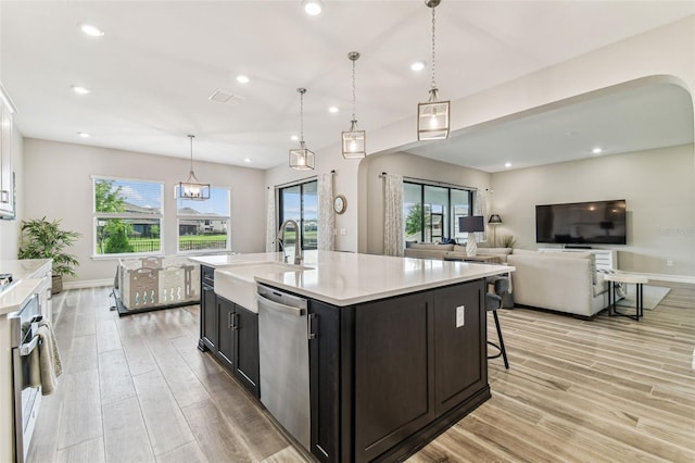 kitchen with a sink, stainless steel appliances, arched walkways, light wood-style floors, and recessed lighting