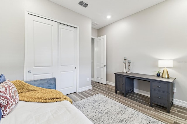bedroom with wood finished floors, a closet, baseboards, and recessed lighting