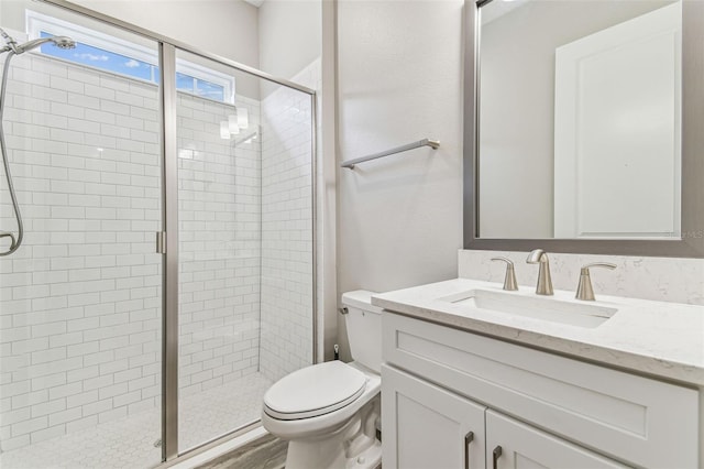 full bathroom featuring a stall shower, toilet, and vanity