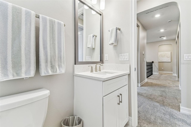 bathroom with vanity, toilet, baseboards, and recessed lighting