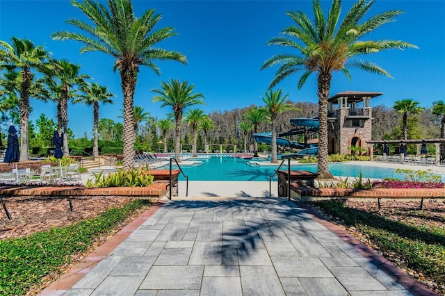 community pool with a water slide and a patio