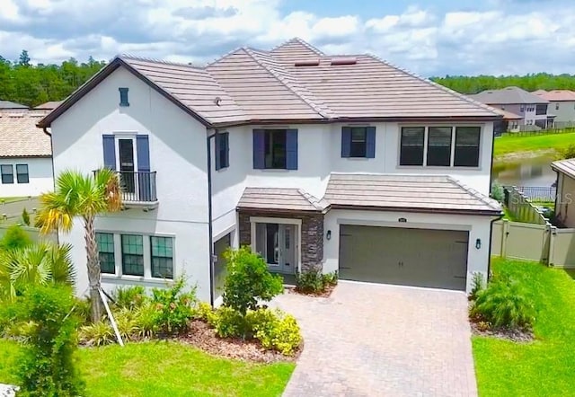 view of front of house with a garage, driveway, stucco siding, fence, and stone siding